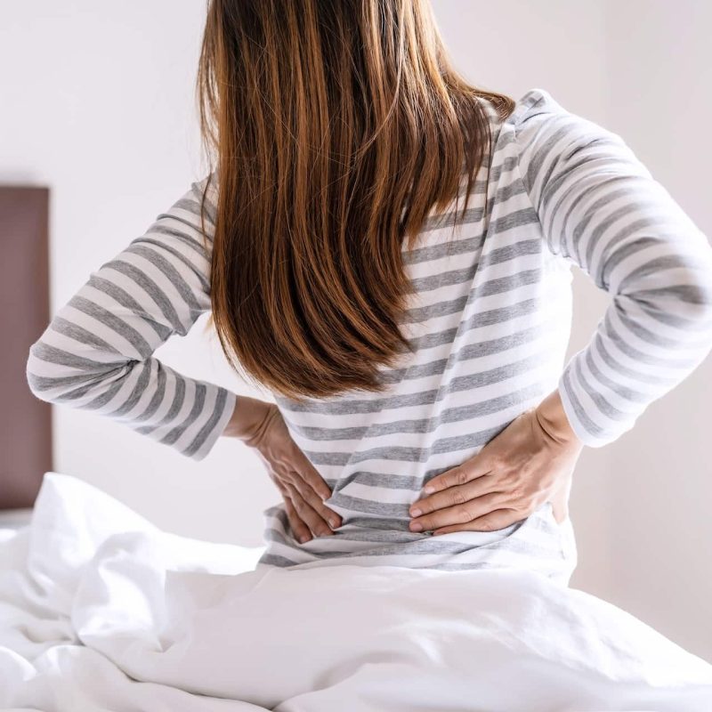 Woman suffering from back ache on the bed in the morning, healthcare and problem concept