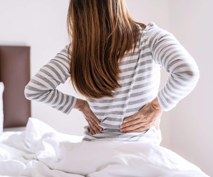 Woman suffering from back ache on the bed in the morning, healthcare and problem concept