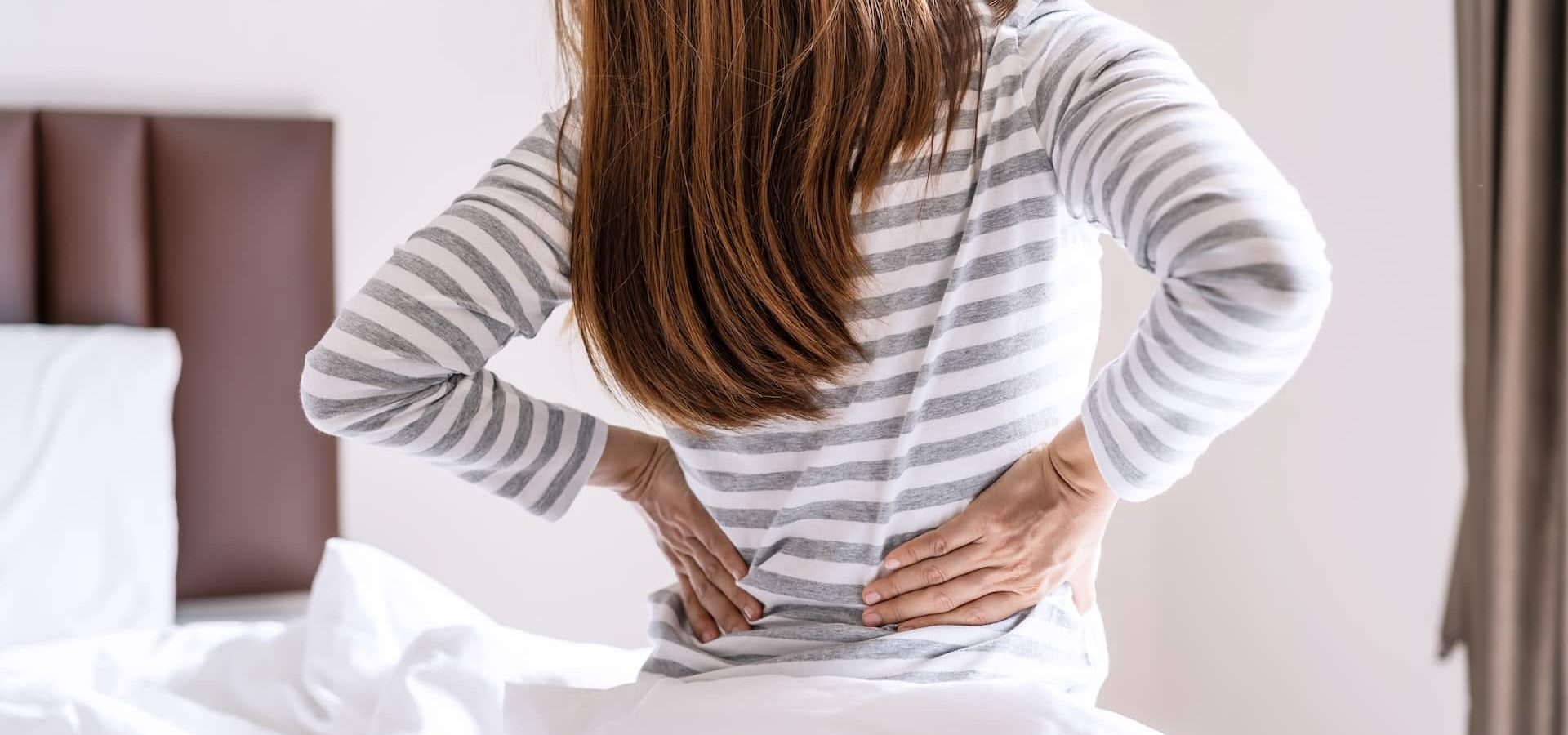 Woman suffering from back ache on the bed in the morning, healthcare and problem concept