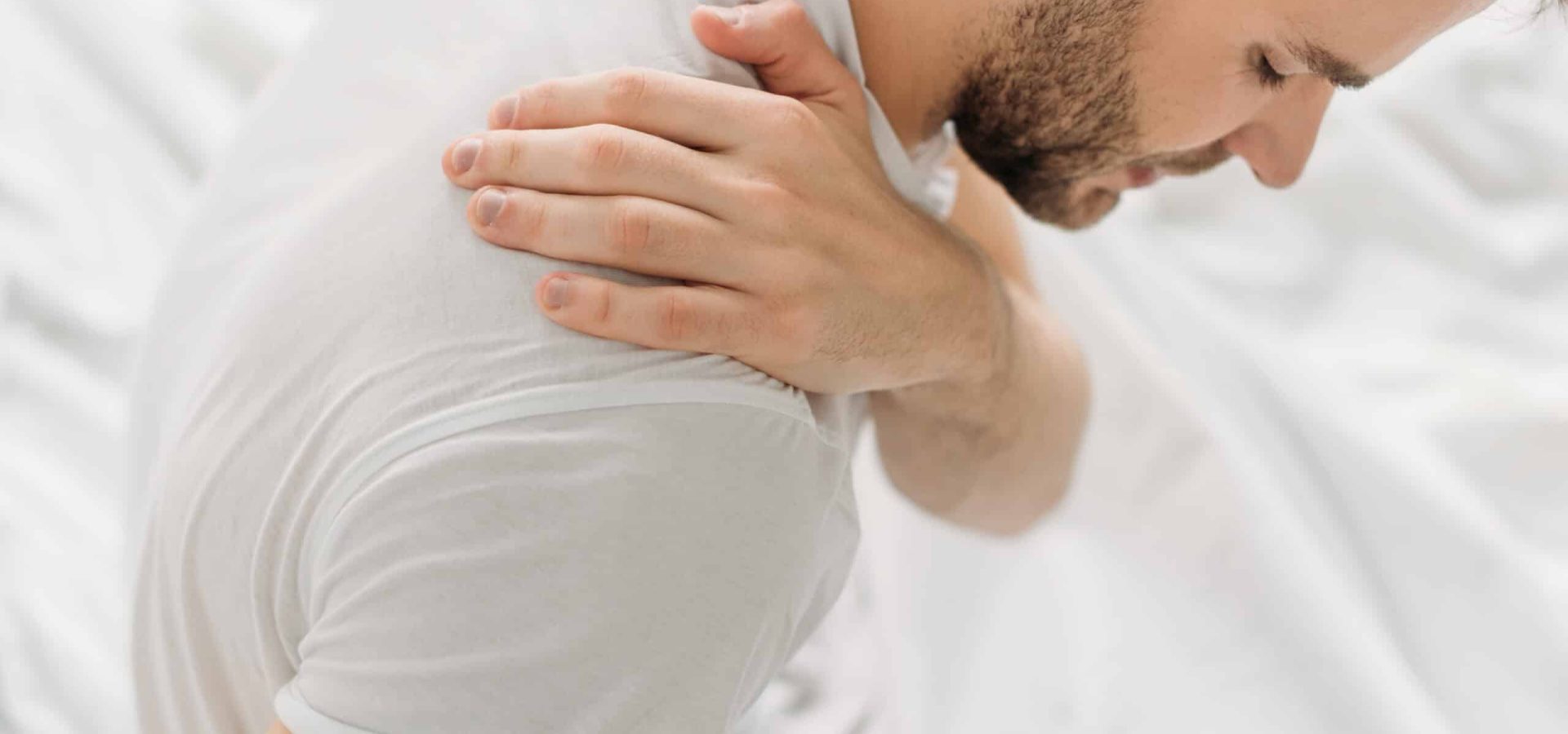 overhead view of man touching shoulder while suffering from pain overhead view of man touching shoulder while suffering from pain